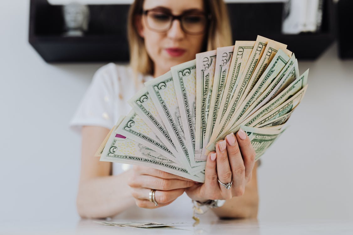 woman holding a wad of cash fanned out